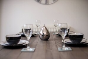 A dining table set with plates, bowls, and wine glasses, centered around a unique pear-shaped centerpiece. - Hillfoot House (Liverpool)