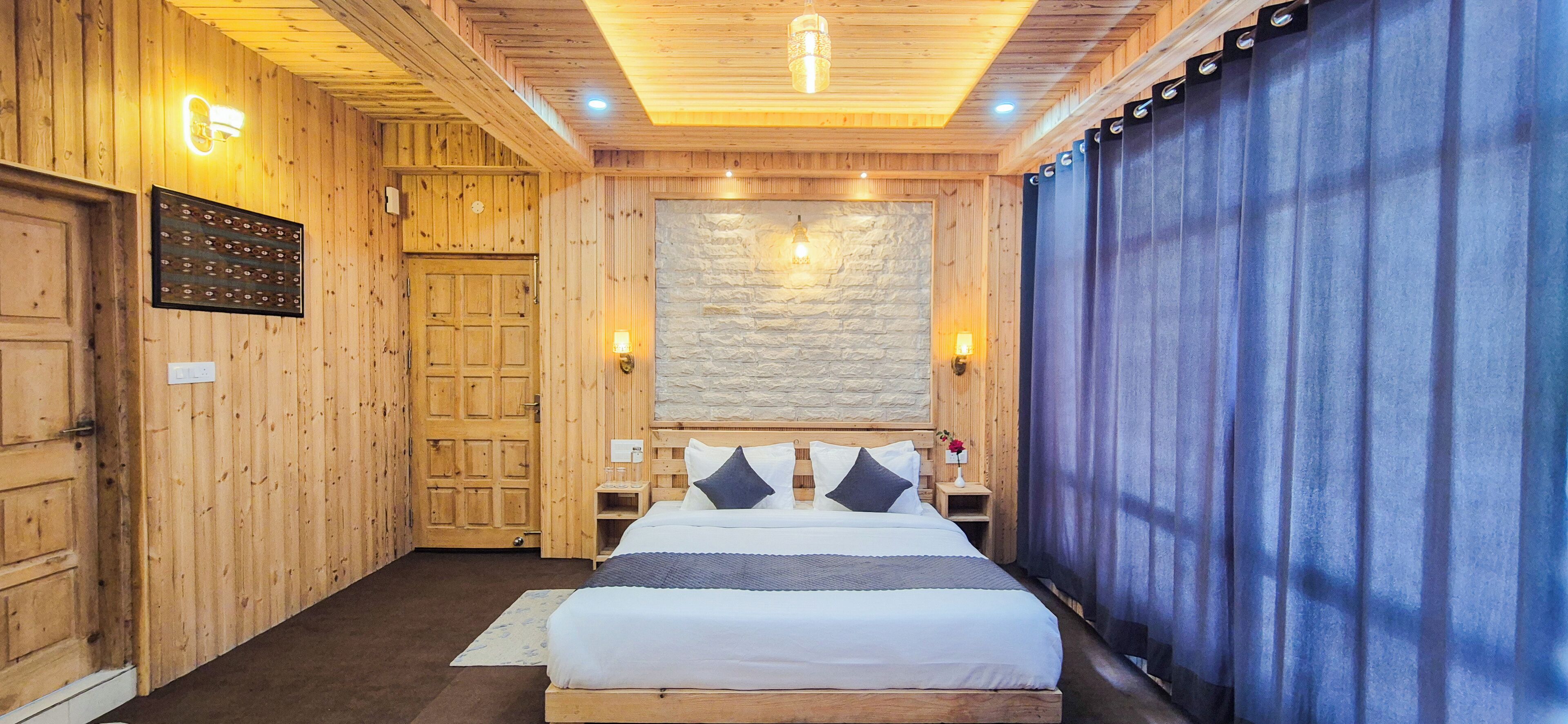 Una habitación de madera con una cama, una pared de piedra y una cortina azul.