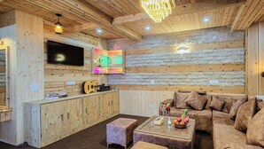 L’intérieur chaleureux d’un chalet, avec un décor en bois, un canapé, une table basse et un téléviseur fixé au mur.
