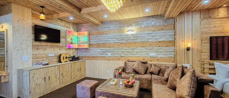 A cozy cabin interior with a wooden interior, a sofa, a coffee table, and a TV mounted on the wall.