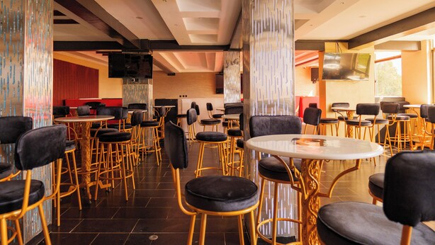 A spacious restaurant with high ceilings, modern decor, and multiple seating areas. - Shanvilla Resort Ltd (Maragua)
