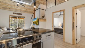 Una cocina moderna con estufa de acero inoxidable, un reloj digital que marca las 5:39, y un cartel que dice 'Bienvenido' sobre una puerta.