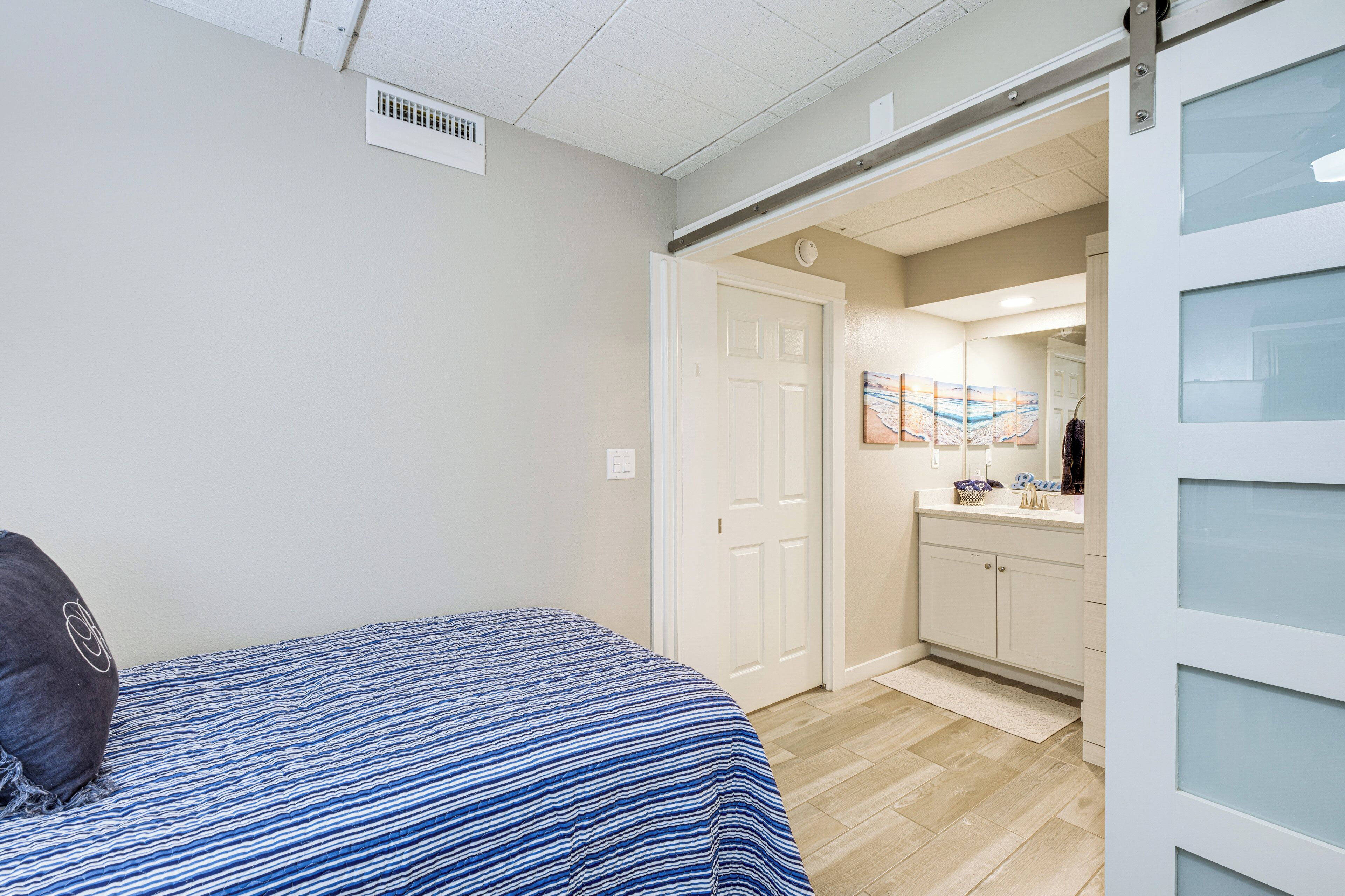 Une chambre avec un lit, une porte donnant sur une salle de bain et un couloir.