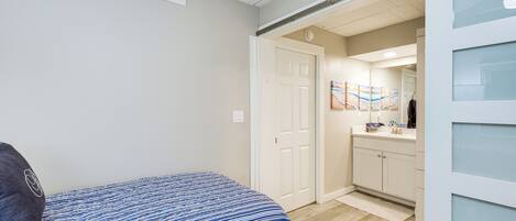 Une chambre avec un lit, une porte donnant sur une salle de bain et un couloir.
