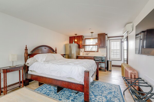 Une chambre avec un lit en bois, un petit bureau, un réfrigérateur, un four à micro-ondes et un radiateur.