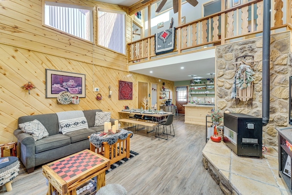Un intérieur de chalet chaleureux avec un plancher en bois, un coin repas, une cheminée et un balcon.