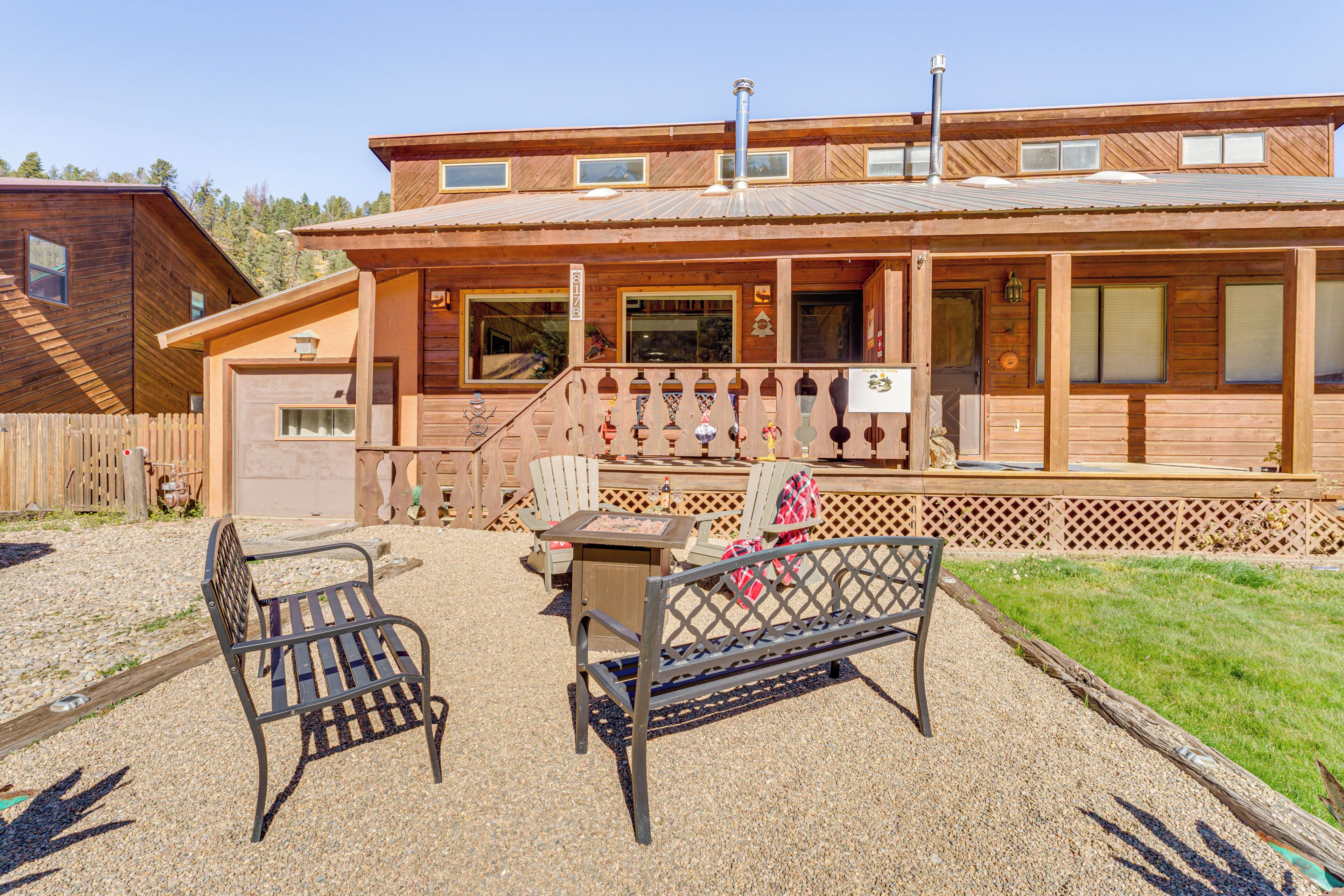 A wooden building with a covered porch, two benches, and a gravel ground.