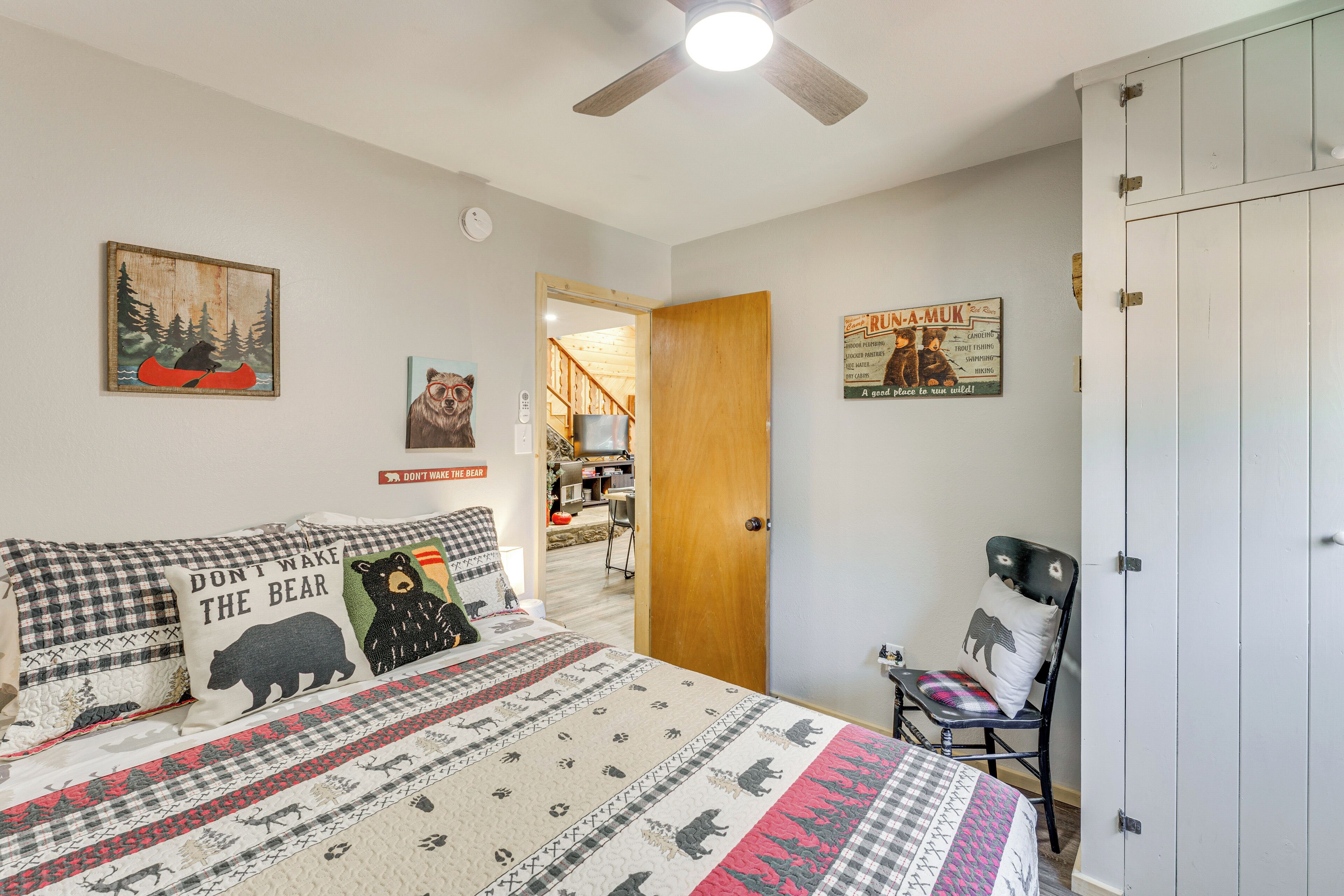 Een slaapkamer met een bed, een stoel, een kledingkast en een deur naar een andere kamer.