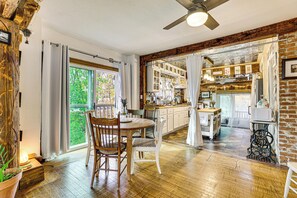 Une cuisine spacieuse avec un plancher en bois, un coin repas avec une table et des chaises, et une vue sur l’extérieur grâce à de grandes fenêtres.