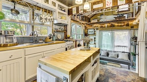 Una cocina con encimeras de madera, ollas colgantes y una isla central con un florero.