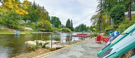 A riverside dock with kayaks, a stone pathway, and a view of the river and surrounding trees.