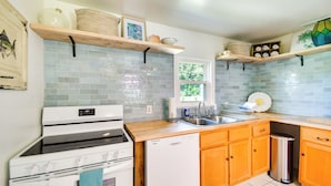 Una cucina con un piano cottura bianco, una lavastoviglie, mobili in legno e una finestra.