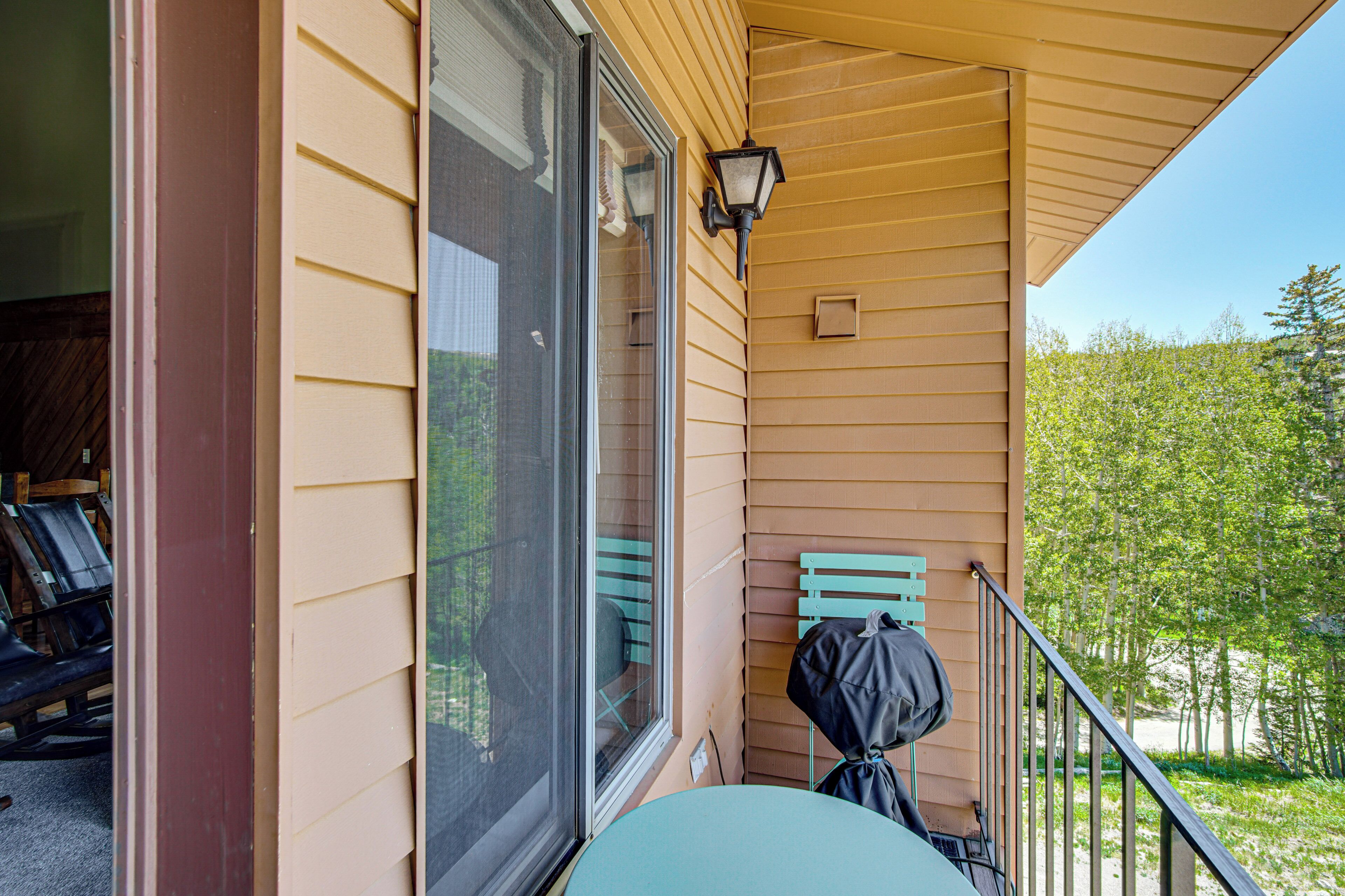 A covered porch with a table, a chair, and a grill.