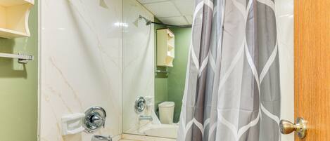 Une salle de bain avec douche, toilettes et lavabo.