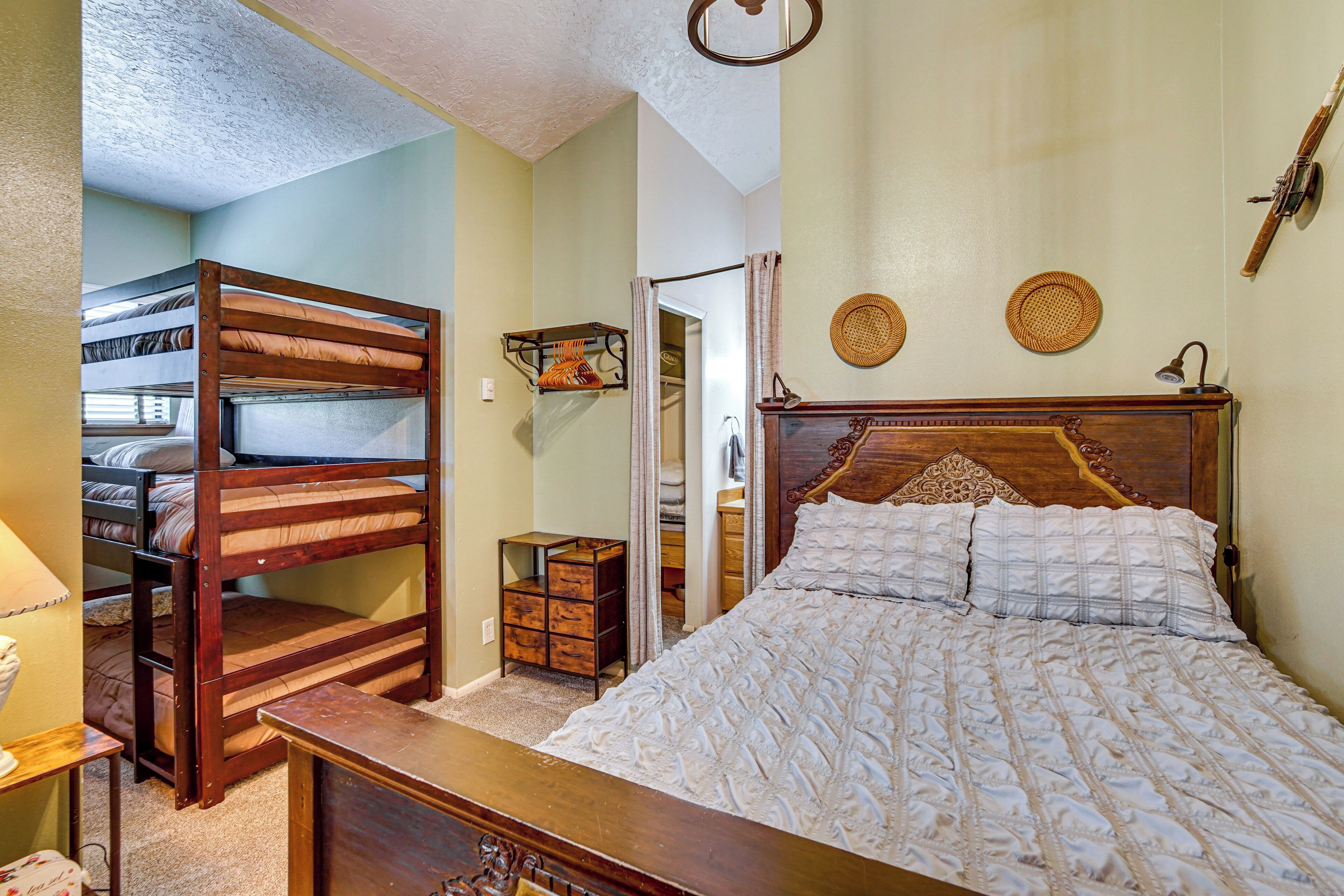 Une chambre à coucher avec un lit superposé, une tête de lit en bois, une table de chevet et une armoire.