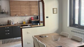 A modern kitchen with wooden cabinets, a built-in oven, and a dining area with a wooden table and chairs.