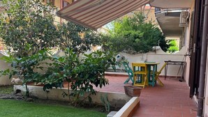 A courtyard with a tiled patio, a small lawn, and a yellow chair.