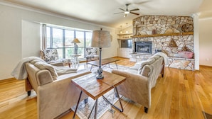 A spacious living room with a fireplace, a dining area, and a kitchen in the background. - Spacious Ruidoso Home w/ Patio & Mountain Views! (Ruidoso)