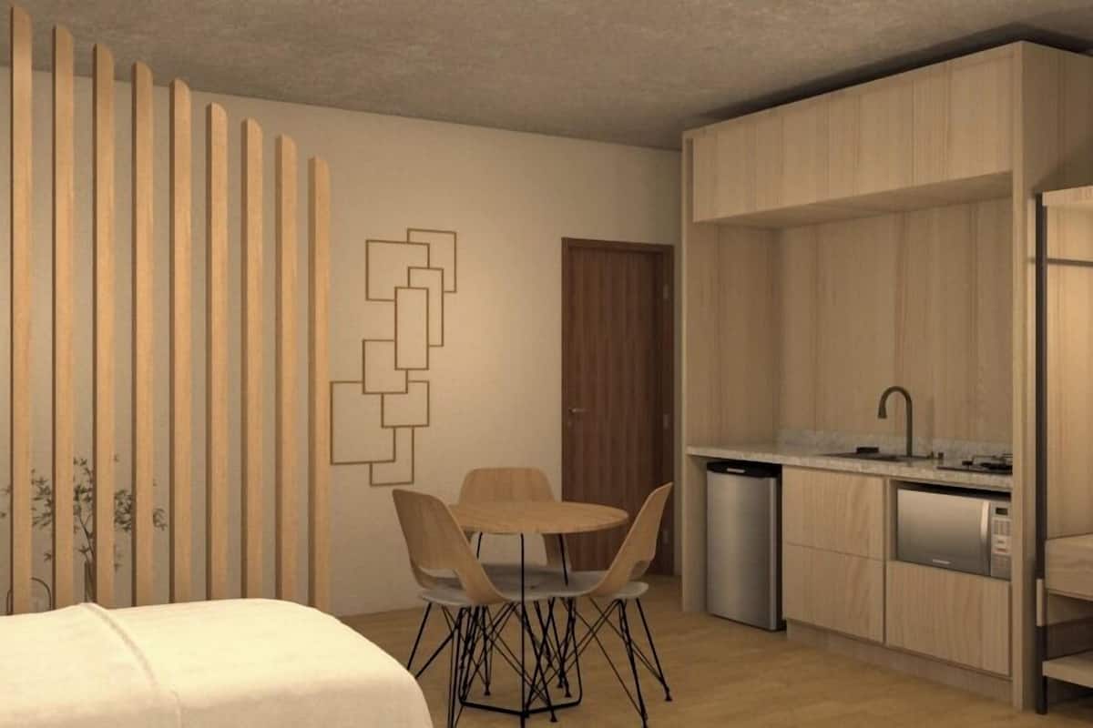 Una habitación moderna y minimalista con un separador de madera, una zona de comedor con mesa y sillas, y una cocina compacta con fregadero y lavavajillas.