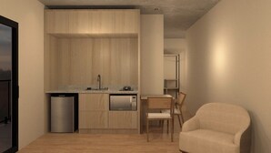 Une cuisine compacte avec des meubles en bois, un four à micro-ondes encastré et un évier. On y trouve un petit coin repas avec une chaise et une table.