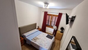 Un dormitorio pequeño y bien iluminado con una cama, mesita de noche y ventana con cortinas.
