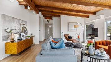 Ein modernes Wohnzimmer mit Holzboden, einem grauen Sofa, einem Couchtisch und einem Fernseher.