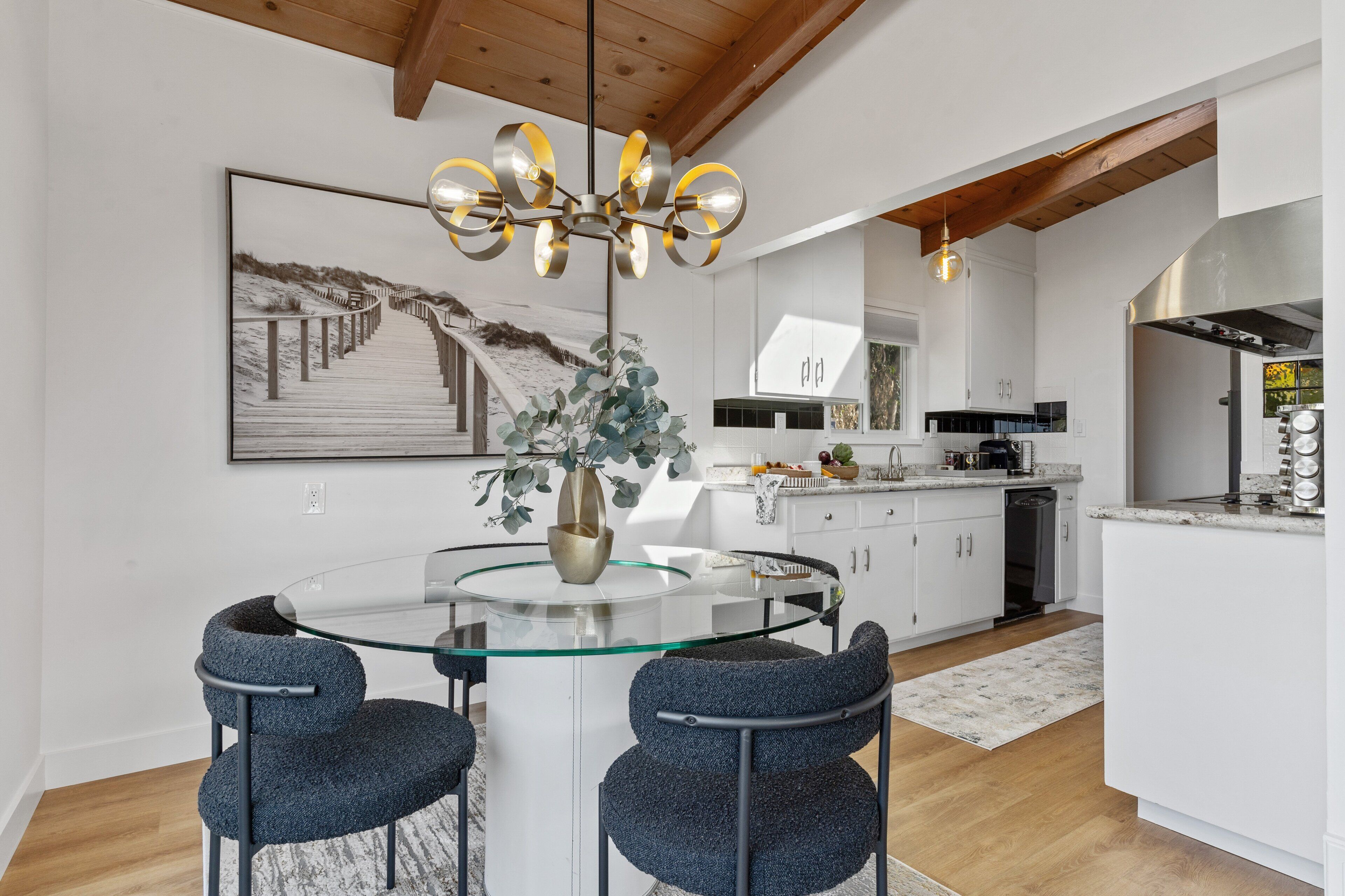 A modern kitchen with white cabinets, a stainless steel range hood, and a built-in dishwasher.