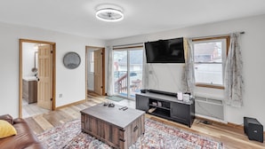 Una sala de estar moderna con una televisión de pantalla plana, piso de madera, un sofá y una mesa de centro.