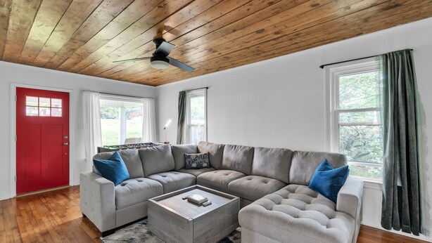 A living room with a sectional sofa, a coffee table, and a red door. - Relax And Unwind In The Heart Of Fayetteville 2 Bedroom Home (Fayetteville)