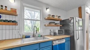 A modern kitchen with blue cabinets, a wooden countertop, a stainless steel refrigerator, and a built-in dishwasher. - Relax And Unwind In The Heart Of Fayetteville 2 Bedroom Home (Fayetteville)