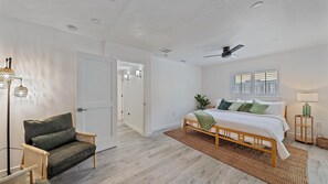 Relax in this serene bedroom with a large bed, woven rug, and ceiling fan for a comfortable stay.