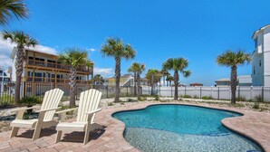 A swimming pool with two Adirondack chairs, surrounded by palm trees and a brick patio. - 🌴☀️Rising Sun | Pet-Friendly Oasis w/ Private Pool + Volleyball Court🏐 (Pensacola Beach)
