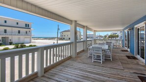 A covered outdoor deck with a table and chairs, overlooking a beach and other buildings. - 🌴☀️Rising Sun | Pet-Friendly Oasis w/ Private Pool + Volleyball Court🏐 (Pensacola Beach)