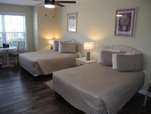 A hotel room with two beds, a desk, and a chair. There are two bedside tables with lamps. - 2703 2 Bedroom Villa (Calabash)