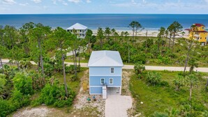 Une propriété située sur la côte, comprenant une petite maison, une plage et une grande maison en arrière-plan.