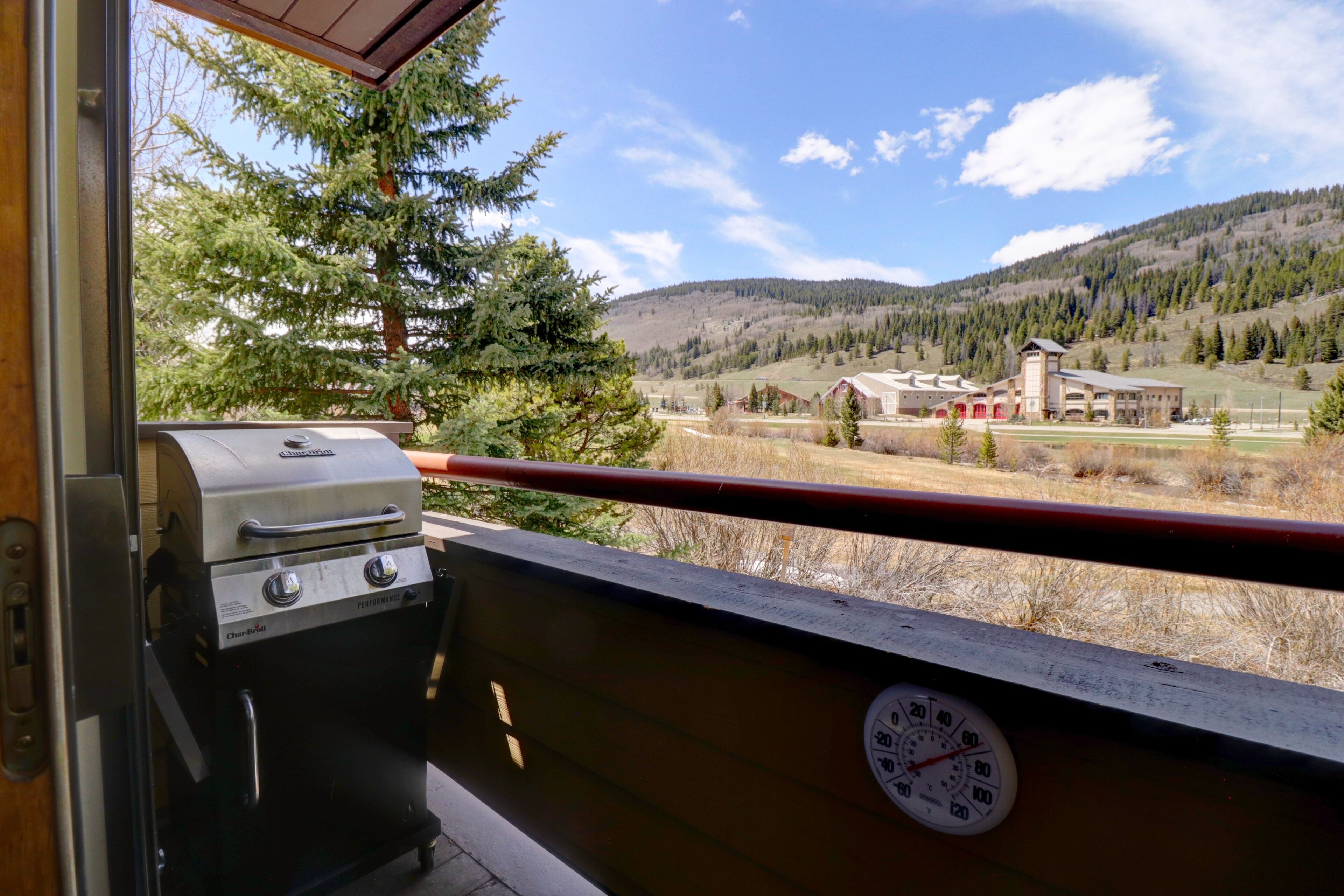 Un balcon offrant une vue sur un paysage montagneux, un barbecue et un thermomètre.