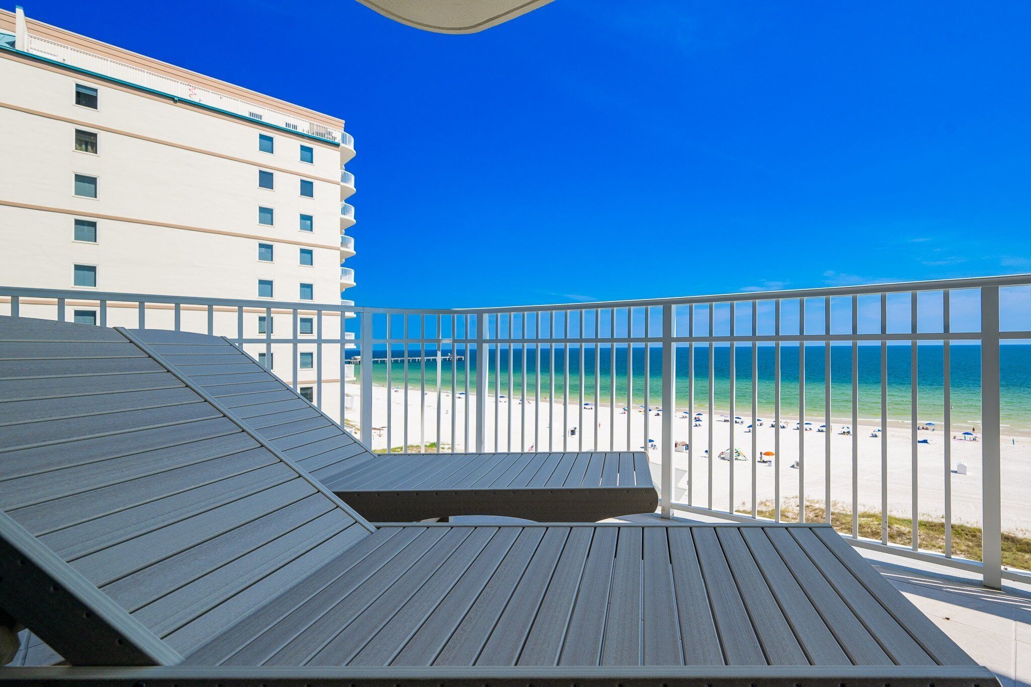 A wooden deck with a view of a beach and a hotel building.