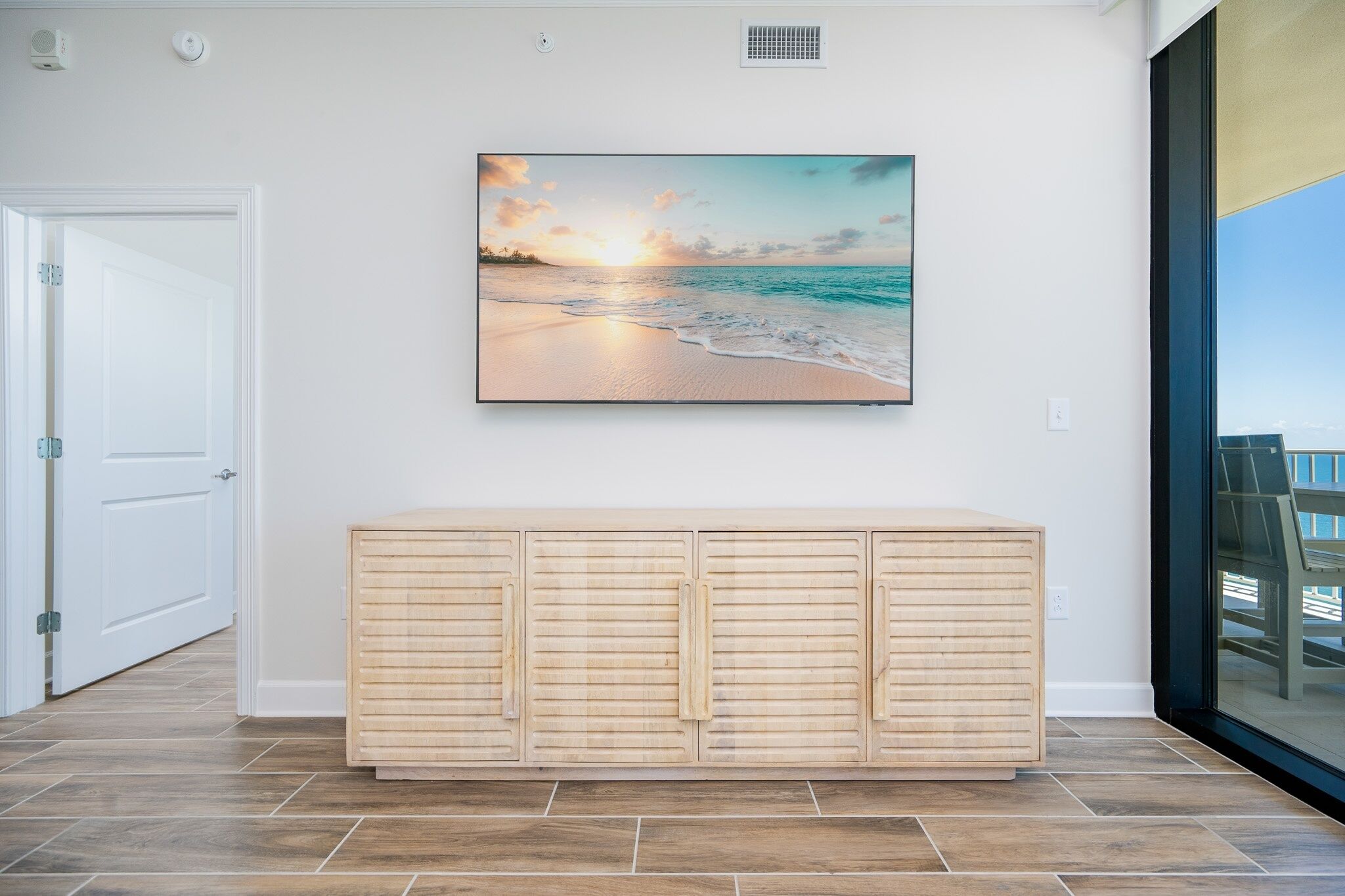 Una habitación con un armario de madera, un cuadro de una playa y una puerta.
