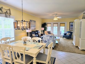 A dining area with a table and chairs, a ceiling fan, and a view of the outdoors through a door.