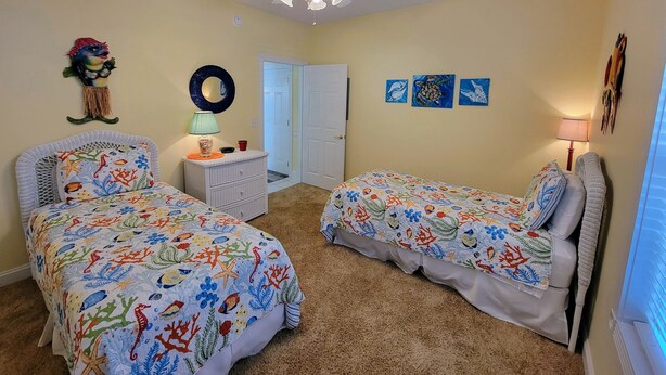 A bedroom with two beds, a ceiling fan, a dresser, and a door. - Peaceful 3BR Ground Floor Condo w/ Intracoastal Waterway Views! (Myrtle Beach)