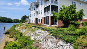 A multi-story building with balconies, a stone retaining wall, and a lake view. - Peaceful 3BR Ground Floor Condo w/ Intracoastal Waterway Views! (Myrtle Beach)
