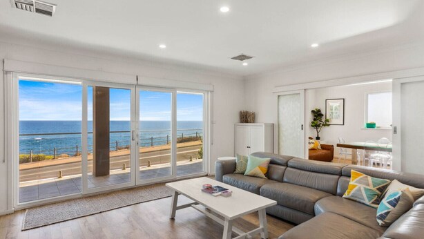 Een woonkamer met een grote schuifpui die uitkomt op een balkon met uitzicht op zee.