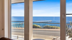Een balkon met uitzicht op de oceaan en een pier.