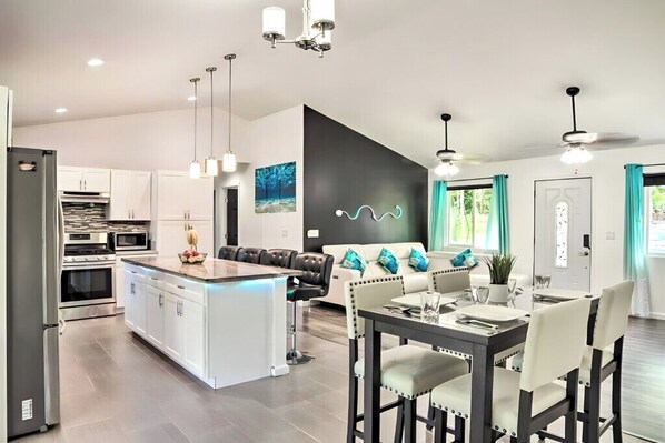 A modern kitchen with white cabinets, a central island, and pendant lighting.