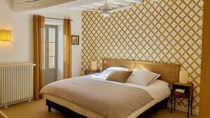 Ein Schlafzimmer mit Bett, Nachttischen, Deckenventilator und einem Fenster mit Vorhängen.