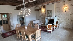 Ein Essbereich mit Holztisch und -stühlen, einer Kristallleuchtre und einem Kamin mit Wandleuchten.