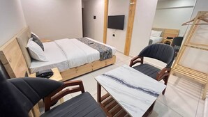 Une chambre d’hôtel moderne équipée d’un lit, d’une petite table, de deux chaises, d’un téléviseur et d’un miroir.