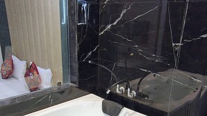Une salle de bain moderne avec une grande baignoire, une douche en verre et un mur recouvert de carreaux de marbre.