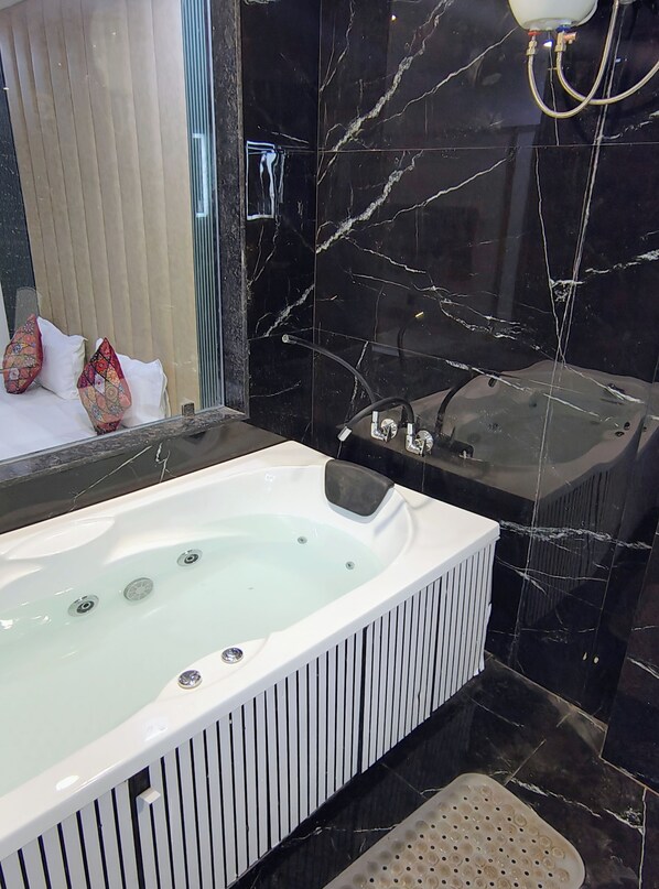 A modern bathroom with a large bathtub, a glass shower enclosure, and a marble-tiled wall. - Hotel Royal Manor-Rajkot (Rajkot)
