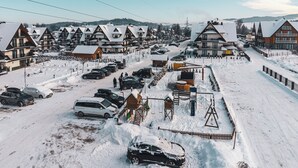 A snow-covered resort with chalet-style buildings, a parking area, and a playground. - Resorts Sun&Snow Białka Tatrzańska P (Bialka Tatrzanska)